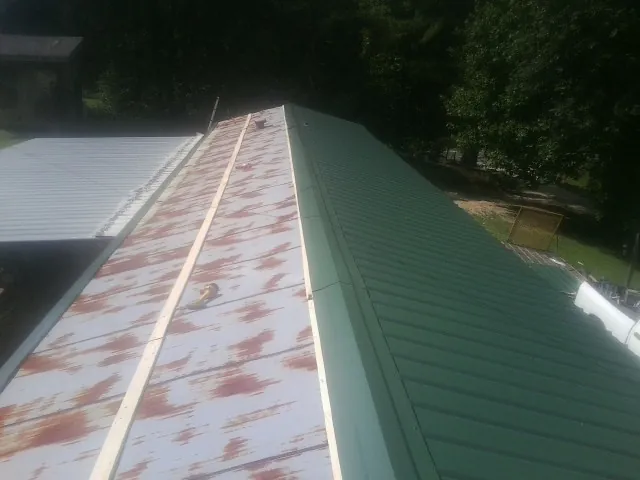 Old rusted panels beside newly installed green metal roofing — Wind Damage Roof Repair by Roofing Brothers in Selma